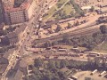 Celkový pohled na prostor dnešní křižovatky dolní Palmovka, kdy byla v provozu ještě železniční trať vedená ulicí Na Žertvách (v pravém horním rohu snímku je vidět budova nádraží) a s ní související železniční přejezd přes Zenklovu ulici | 1976