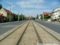 Přímý úsek tramvajové tratě zakryté zádlažbovými panely ve středu Bělohorské ulice.