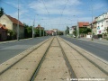 Přímý úsek tramvajové tratě zakryté zádlažbovými panely ve středu Bělohorské ulice.