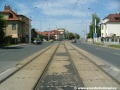 Přímý úsek tramvajové tratě zakryté zádlažbovými panely ve středu Bělohorské ulice.