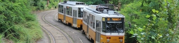 Souprava vozů T5C5 ev.č.4290+4293 vypravená na linku 12 levým obloukem stoupá z podjezdu pod tratí linky 14 k zastávce Rákospalota-Újpest vasútállomás. | 25.6.2014