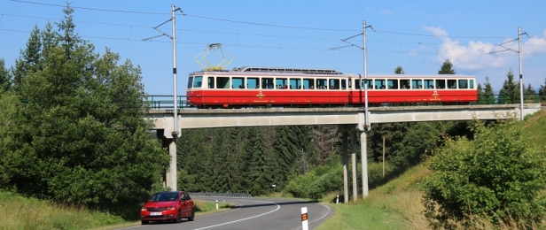 Přes most nad silnicí do Liptovského Hrádku stoupá na Štrbské Pleso jednotka ozubnicové železnice 405 952-3+905 952-8. | 10.7.2018