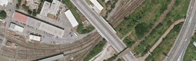 Na leteckém snímku vidíme rozsáhlé kolejiště odstavného železničního nádraží Praha-Jih s mostem, který nad ním převádí vozovku Chodovské ulice.