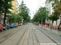 Tramvajová trať tvořená velkoplošnými panely BKV pokračuje ve středu vozovky ulice Komunardů v přímém úseku