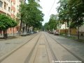 Tramvajová trať tvořená velkoplošnými panely BKV pokračuje ve středu vozovky ulice Komunardů v přímém úseku