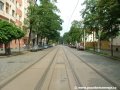 Tramvajová trať tvořená velkoplošnými panely BKV pokračuje ve středu vozovky ulice Komunardů v přímém úseku