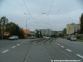 Tramvajová trať tvořená žlábkovou kolejnicí NT1 se stáčí v prostoru přejezdu pro automobily na křižovatce s Bazovského ulicí