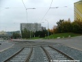 Tramvajová trať se v levém oblouku přibližuje k přejezdu pro automobily před zastávkou Slánská
