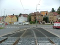 Tramvajová trať ve žlábkových kolejnicích NT1 překračuje levým obloukem světelně řízenou křižovatku s Plzeňskou ulicí