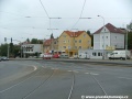 Tramvajová trať ve žlábkových kolejnicích NT1 překračuje levým obloukem světelně řízenou křižovatku s Plzeňskou ulicí