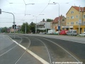 Tramvajová trať ve žlábkových kolejnicích NT1 překračuje levým obloukem světelně řízenou křižovatku s Plzeňskou ulicí