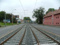 Tramvajová trať v levém oblouku klesá ve středu Plzeňské ulice a napřimuje se