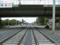 Tramvajová trať v otevřeném svršku podchází most, který nad Plzeňskou ulicí mimoúrovňově převádí Bucharovu ulici