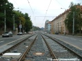 Tramvajová trať tvořená otevřeným svrškem klesá středem Plzeňské ulice.