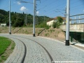 Vratný oblouk smyčky Podbaba se přibližuje k náspu železniční tratě.
