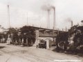 Ve vratech hlavní brány Ringhofferovy továrny u Plzeňské ulici stojí posunovací akumulátorová lokomotiva č.2 a na snímku je dokonale patrné také křížení s tramvajovou tratí | 1920